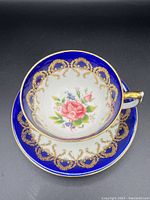 Top view showing the pink rose design inside the teacup, surrounded by cobalt blue and gold gilt detailing on rim.