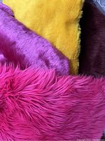 Close-up of four pieces of faux fur in bright pink, hot pink, yellow, and burgundy.