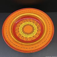 Top and angled view of large 13 inch mid century Italian ceramic bowl with vibrant orange and yellow concentric circles and leaf-like patterns.