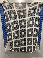 Full view of the large crochet bedspread held up vertically to show overall size and pattern.