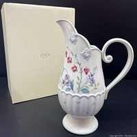 Three-quarter side view of white porcelain Lenox pitcher with floral Spring Bouquet pattern and original box behind it.