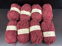 Eight skeins of red wool yarn with Pingouin brand labels, arranged in two rows.