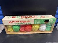 Original Astralite Partio Lights box showing six blow mold patio lights in assorted colors, with packaging details visible.