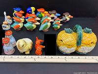 Overview of the full collection arranged with measuring ruler showing scale and variety of vintage salt and pepper shakers including colorful birds, pineapples, and other figures