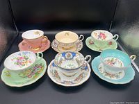 Six E.B. Foley Bone China teacups and saucers arranged in two rows, showing different colors and handpainted floral and gilt designs.
