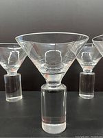 Front close-up view of one martini glass showing clear crystal bowl and thick cylindrical base, highlighting design and condition.
