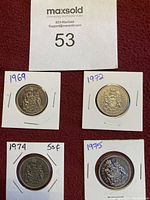 Photo showing four 50 cent coins from years 1969, 1972, 1974, and 1975, each secured in paper holders.