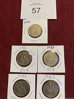 Five 50 cent coins in individual white cardboard holders with handwritten year notations: 1976, 1981, 1982, 1983, and 1984. Coins have a crest design and are in good condition.