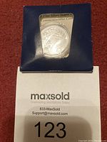 Front view of the $20 Silver Maple Leaf Commemorative Coin in blue holder showing the coin with maple leaf design and the denomination visible.