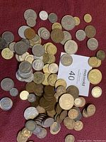 Photo shows a large collection of mixed European coins scattered on a red surface with a MaxSold lot card number 40 visible.