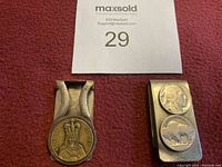 Two metal money clips on red fabric background; one with King Edward VII coin design and the other with buffalo and profile coins.