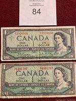 Front view of two Canadian one dollar bills from the Bank of Canada, showing Queen Elizabeth II's portrait and serial numbers.