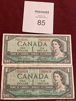Front side of two Canadian one dollar bills showing portrait of Queen Elizabeth II and serial numbers