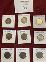 Photo showing nine USA quarter dollar coins in white 2x2 holders, each labelled with the state name including Virginia, Rhode Island, West Virginia, District of Columbia, Oregon, Arizona, Tennessee, Virginia (duplicate), and New York.