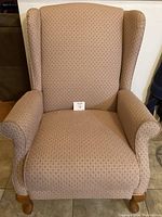 Front view of pink upholstered recliner chair in upright position