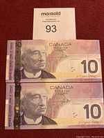 Front side of two Canadian ten dollar bills placed one above the other showing Sir John A. Macdonald portrait, serial numbers partially visible.