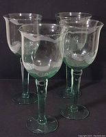 Four pale green blown crystal goblets arranged in a cluster showing their full height and shape.