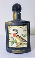 Full front view of black ceramic Jim Beam whiskey bottle with stopper showing wood duck illustration and label.
