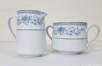 Front view of cream pitcher and sugar bowl with blue floral and platinum trim