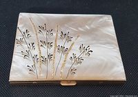 Clear photo of the cigarette case closed showing detailed mother of pearl inlay floral pattern with gold accents on brass frame