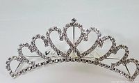 Small silver-tone metal tiara adorned with clear rhinestones, showing front heart pattern design.
