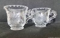 Front view of the creamer and open sugar bowl, showing etched cornflower pattern and beaded handles