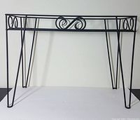 Front angled view of the wrought iron plant stand showing the scroll decorative element and tapered legs.