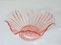 Pink Depression glass candy dish with fluted sides, scalloped edge, and footed base shown from top angle