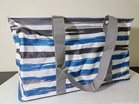 Side view of large open top tote bag with blue, gray, black, and white brushstroke stripes and two long gray handles.