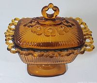 Front angle showing amber glass candy dish with filigree edge and decorative lid handle