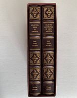 Front view of two leather-bound volumes with gilt embossed spines titled 'Selected Birds of America' and 'Selected Quadrupeds of North America' by John James Audubon in a matching leather slipcase.