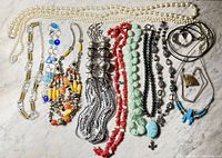 Photo showing the entire lot of costume jewelry consisting of 21 pieces including necklaces and bracelets arranged on a marble surface.