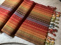 Table runner folded to show colors and tassel details on a marble surface.