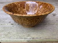 Front angle view of a large brown spongeware pottery bowl showing inner glaze and outer textured pattern.