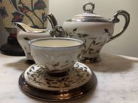 Photo showing the Sadler tea set including teapot, creamer, teacup, saucer, and plate with old silver lustre decoration and foliage motifs.