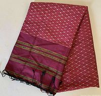 Full view of the large burgundy silk scarf showing the white diamond pattern and striped border with black fringe tassels.