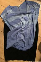 Photo of blue patterned T-shirt laid over black wool skirt, showing material and color detail.