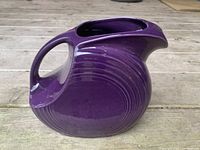 Side view of grape purple vintage Fiesta Ware ceramic pitcher showing bulbous body, curved handle, and spout