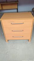 Front view of Ikea Boksta 3-drawer chest showing wood finish and metal handles