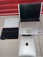 Dell XPS M1330 laptop, Apple iPad, and iPad keyboard case displayed on a table