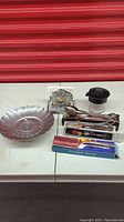 Full assortment of kitchen gadgets on table including citrus juicer, salt and pepper shakers, toothpick holder with napkin holder, vegetable steamer, lasagna server in box, cake tong, salad tong, and glass bowl.