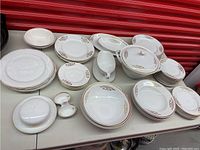 Wide angle photo of full set of dishes on a table showing multiple plates, bowls, a covered serving dish and gravy boat with gold painted decoration.