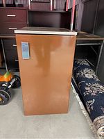Brown vintage Danby Ignis mini fridge with wood-look top surface shown front closed.