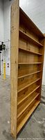 Side view of one tall pine bookcase showing seven shelves and natural wood grain.