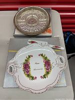 Full view of the porcelain tray with floral pattern and Happy Anniversary text, cake cutter, and silver-plated tray on a box.