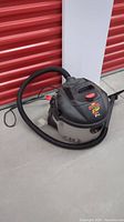 Shop Vac Plus wet/dry vacuum positioned on ground, showing overall shape and hose.