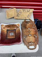 Set of 4 trays including two wicker baskets, one glass tray, and one olive wood carved tray
