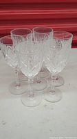 Set of six vintage crystal goblet wine glasses arranged in a cluster showing their shape and clear faceted cut design.