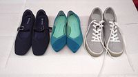 Three pairs of women's shoes aligned side by side showing blue slip-ons, teal flats, and gray sneakers.