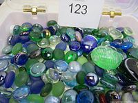 Top view of assorted mixed color flat glass pebbles and marbles in a container, showing variation in color, size and finish.